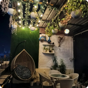 Fairy-lit hanging plants and rattan swing chair on the Pepper Pot Café terrace at night