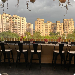 Terrace bar seating with a Gurugram skyline view at Pepper Pot Café